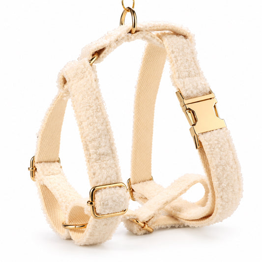 Adjustable ivory teddy fleece dog harness with gold-tone buckle, metal rings and soft cream-colored lining.