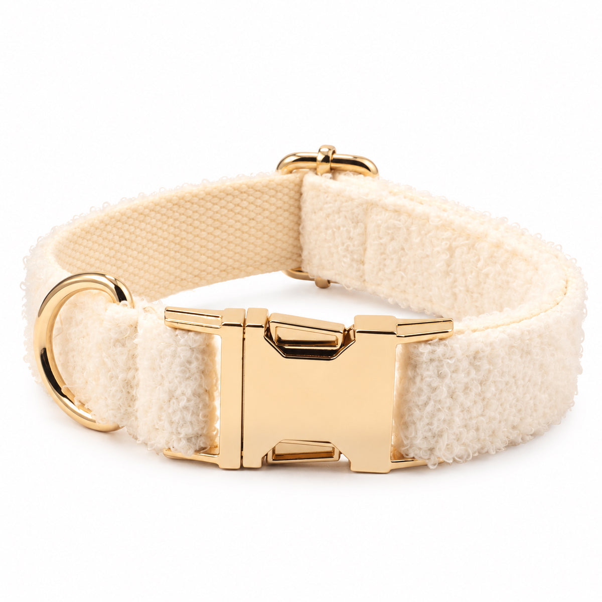 Close-up of an adjustable ivory teddy fleece dog collar featuring a polished gold-tone buckle and D-ring.