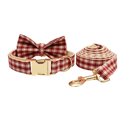 Matching red and cream plaid dog collar with bow tie and leash set featuring gold hardware on a white background.