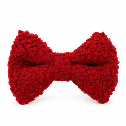 Close-up of a red teddy fleece dog bow tie featuring soft, curly textured fabric on a white background.